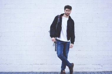 Tam uzunlukta metin mesajı reklam için kamera ile promosyon arka plan beyaz duvar yakın dururken bakarak kendine güvenen genç öğrenci portresi. Yakışıklı genç Açık havada dinlenme