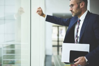 Yakışıklı işadamı iş başlangıç projesi, office dijital tablet tutan penceresinde yakın duran müreffeh emin erkek girişimci için yaratıcı çözüm yapma hakkında düşünme belirlenir 