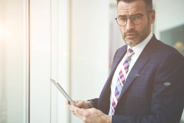 Gözatma bilgilerinin ve finans haberleri online, yakışıklı işadamı para işlem yapmak için uygulama kullanarak izleme için dijital tablet kullanarak emin erkek girişimci portresi