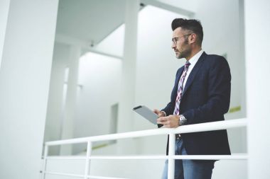 Dalgın şık giyimli erkek girişimci iş gezisi, gurur CEO'su çalışanın online iş denetimi için bilet rezervasyonu için dijital tablet ve wifi bağlantısı kullanarak uygulama touchpad üzerinde kullanarak.