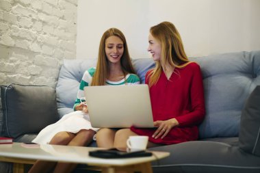 Neşeli çekici meslektaşları oturan Divan, dostane bir atmosferde pozitif kadın boş zaman zaman birlikte Cafe iç zevk video izlerken zevk ortak proje hakkında tartışma