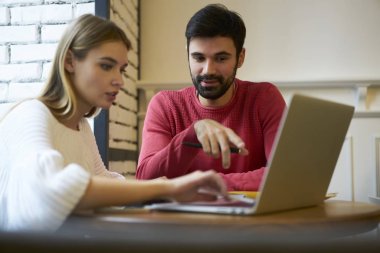 Düşünceli çekici kadın ve yararlı bilgi web sitesinde kablosuz internet'e bağlı ve kafeterya gayri resmi toplantıda fikirleri tartışmak dizüstü bilgisayarda okuma olumlu sakallı adam