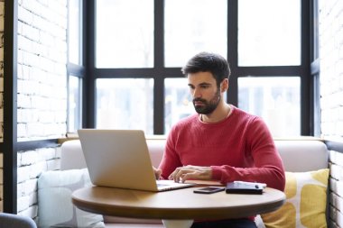 Yakışıklı yetenekli geliştirici eğitim webinar üstünde laptop wifi için bağlı web sayfasındaki izlerken durulması. Profesyonel uzaktan çalışırken yararlı bilgiler web sitelerinde arama metin yazarı sakallı