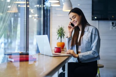 Dijital macbook bilgisayar başında oturan ve kafede yaklaşan sınavlar için hazırlanıyor süre dostu modern smartphone ile konuşmayı uzun güzel esmer saçlı neşeli öğrenci