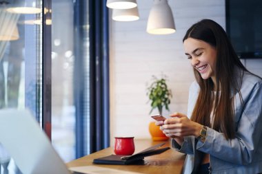 Neşeli hippi kız online cep telefonu dizüstü bilgisayar şık kafede oturan yüksek hızlı internet bağlantısı için bağlantı üzerinde arkadaşlarınızla sohbet. Pozitif öğrenci üzerinde hücresel mesajlaşma