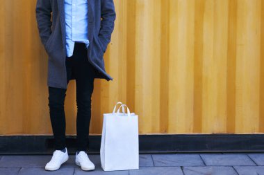 Kırpılmış görüntü, trendy giyim marka adı veya logosu, iyi görünümlü genç erkek kentsel ortamda arka plan üzerinde duran sahte yer ile kamera için poz giyen hipster adam