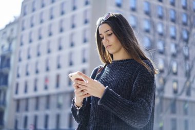 Güneşli havalarda şehir sokaklarında dolaşmak şehirde gezinmek için akıllı telefon kullanan esmer kız. Genç kadın turist açık havada taksi çağırmak için mobil uygulama bildirimini kontrol