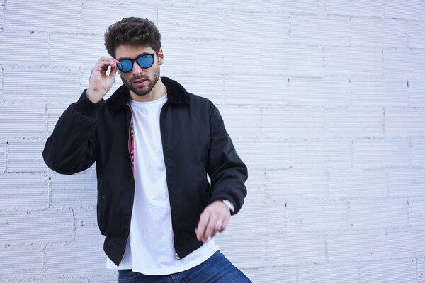 Half length portrait of confident handsome male dressed in fashion clothing looking at camera while enjoying leisure time standing against colorful background with copy space for promotional content