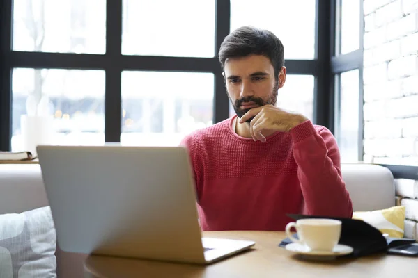 Nadenkend Gebaarde Mannelijke Ondernemer Gekleed Rode Trui Nuttig Browsegegevens Laptop — Stockfoto