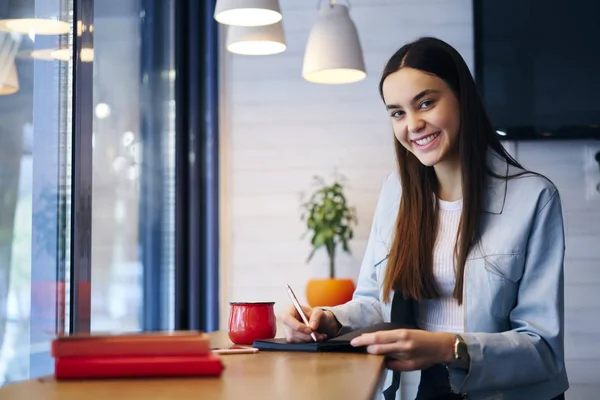 Retrato Estudiante Inteligente Positivo Sonriendo Cámara Mientras Escribe Información Cuaderno — Foto de Stock