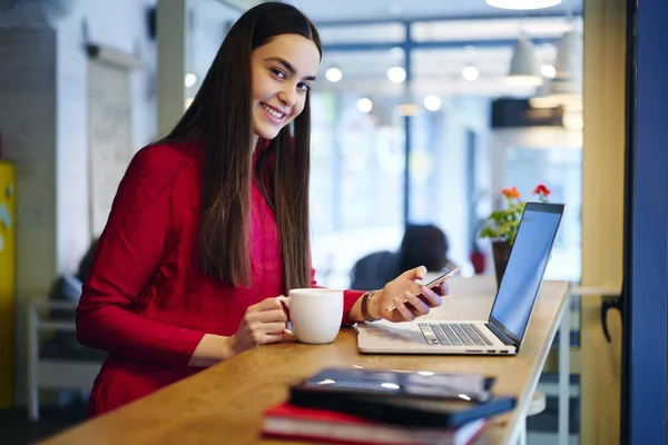 微笑的黑发女性雇员的画像休息在咖啡打破博客在社交网络通过移动 熟练的女实业家从安装在智能手机上的应用程序检查财务消息 — 图库照片