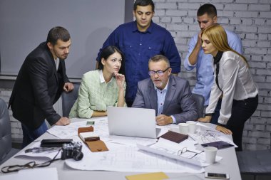 Takım vasıl okul sırası ofiste oturan yeni bina projesi çizimler üzerinde birlikte ise Yönetim Kurulu toplantısı sırasında macbook bilgisayarda sunum izlerken başarılı erkek ve dişi Mimarlar