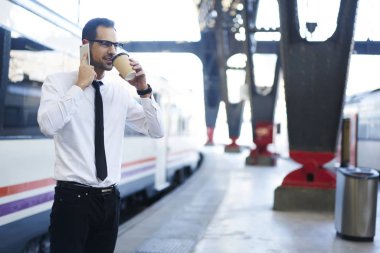 Smartphone tren istasyonunda konuşan işadamı