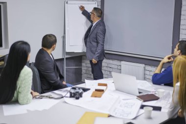 Sağlayan ve Pano bilgileri sunu tahta karşı ayakta meslektaşları için yazma Olgun deneyimli erkek müdürü. Yetenekli koç eğitim çalışanları için resmi toplantı yapma