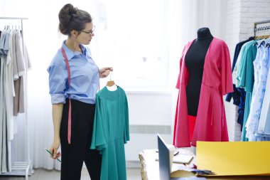 Manken modacı profesyonel görünümlü elbise örnek iyileştirilmesi üzerinde durulması yaratıcı düşünceli esmer Tasarımcı giyim modeli modern stüdyo ekipmanları ile terzilik üzerinde konsantre