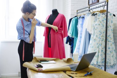 Atelier manneken, yetenekli tasarımcı showroom ile aletleri durulması uygun malzeme hakkında düşünme yakınındaki yeni modeli ayakta oluşturma işleminde çalışan profesyonel terzi konsantre