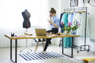Genç başarılı atelier sahibi olumlu havanın üstünde duran Studio smartphone telefon konuşmayı gözlükler. Telefonla çalışmaları sırasında kapalı konuşurken yetenekli kadın tasarımcı