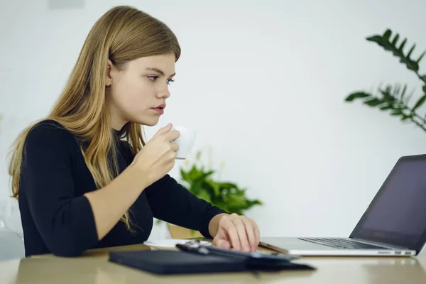 在办公室里坐着膝上型电脑的金发女郎的沉思的年轻女子 聪明的女学生浏览互联网网站上的现代设备 为广告文本复制空间区域留言 — 图库照片