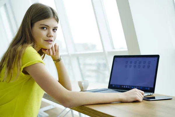 半长肖像美丽的金发女人看着相机 而远亲工作在笔记本电脑与模拟屏幕连接到 Wifi 在咖啡馆里使用现代技术的年轻天才学生 — 图库照片