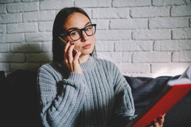 Not defteri tutan ve konuşmayı meslektaşı ile telefon, cep telefonu görüşmesi sırasında kameraya bakarak gözlük kız öğrencinin çalışma programı düzenlenmesi ciddi iş kadın portresi