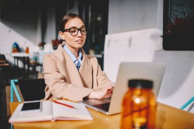 Uzak iş dizüstü bilgisayar, kendine güvenen kadın sahibi haber ağları online yazım geribildirim netbook üzerinde okuma kafe iç kontrol postada sahip gözlükler başarılı iş kadını