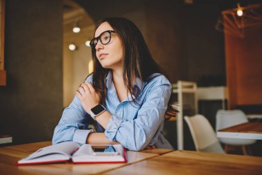 İş planı süre bilgi öğrenme ve Üniversite Kampus içinde ödev rüya Cafe iç, düşünceli kız öğrencinin Not Defteri'nde ile oturan üzerinde durulması gözlük dalgın kadında