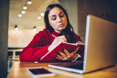 Uygulama verileri kullanarak ve dizüstü bilgisayar, not defterinde web sayfasından bilgi yazma öğrenci üzerinde muhasebe yetenekli kadın grafik tasarımcı çizim kroki netbook üzerinde online dersler sırasında göz.