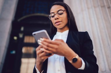 Afrika kökenli Amerikalı girişimci görünümü altında hizmet smartphone aygıt açık havada duran bankacılık yoluyla online ödeme yapmadan şık takım elbise giymiş. Uygulamasını kullanarak cep telefonundan işkadını