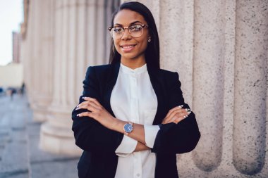 Yarım uzunluk portre üzerinde başarılı işkadını elleri katlanır ve kameraya bakarak formal giyim giymiş. Kamera açık havada duran gülümseyen Eyewear müreffeh profesyonel Finans Müdürü