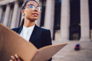 Optik gözlükler belgeleri uzak duran kopya alanı ile kentsel ortamda arıyor tutmak düşünceli Afro-Amerikan işkadını. Kadın koyu tenli öğrenci yüksek ekonomik Üniversitesi