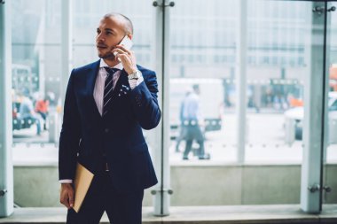 Yakışıklı erkek avukat elinde duran cep telefonu üzerinden telefon konuşmayı şık elbiseli emin kurumsal işadamı Manhattan'ın Caddesi üzerinde şehir merkezinde, arama klasörü belgelerle