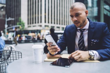 Emin erkek girişimci mali Satım sırasında iş ara, iş adamı açık havada online ödeme yapmak için mobil bankacılık hesabınızı kontrol smartphone web sayfasında tarama haber okuma