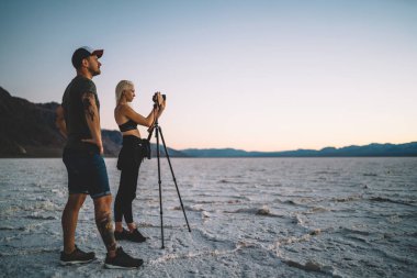 Erkek ve kadın turist Badwater Milli Parkı doğal manzara resmi akşam, profesyonel blogcular kamera tripod yolculuğa birlikte olma ile video çekim yapma gitmekten zevk