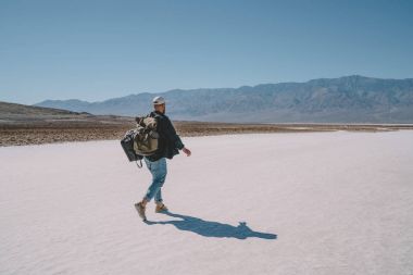 Arkadan erkek traveler Ulusal Park california ABD kuru topraklarda yürüyüş turistik arka çantalar, adam beyaz tuz ile Badwater havzasının doğal peyzaj ölüm Göl yüzeyinde keşfetmek taşıyan görünüşü