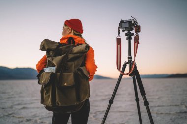 Modern ekipman ve tripod kullanarak Badwater Havzası fotoğrafını çekmek kadın doğal ortamının video çekmeye başlamadan önce hazırlık yapma sırt çantası ile kadın fotoğrafçı arkadan görünüm 