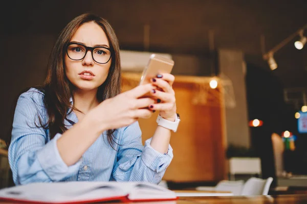 照片中愤怒的女学生的肖像震惊与获得票据收据的手机邮件 情绪年轻的妇女强调与电话应用程序失败看相机花时间在咖啡馆 — 图库照片