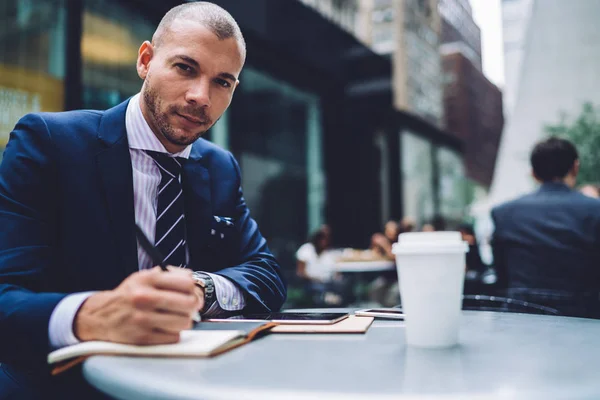 一个自信的白种商人的肖像坐在咖啡馆的餐桌上咖啡休息时 英俊的男性执行经理制定计划在户外的记事本上写笔记 — 图库照片