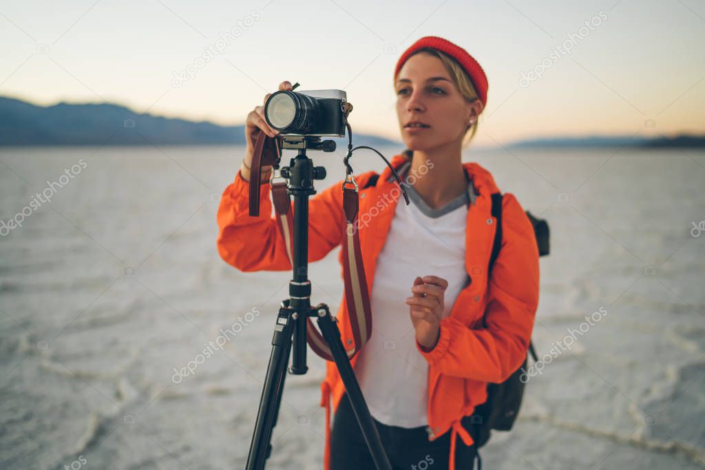 Concentrated female photographer making settings before shooting vieo of scenic nature of Badwater national park in USA, skilled woman taking pictures of landscape of dry lake in Death Valley
