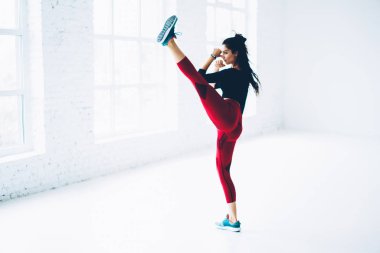 Çekici kadın savaşçı eğitim gücü alt beden hedefleri ile motive genç sporcumuz kickboks beyaz iç studio mükemmel vücut tutmak için belirlenen egzersiz pratik