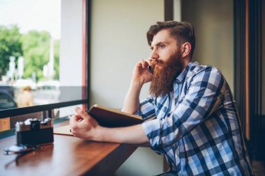 Genç cep telefonu kafede favori kitap okuma sırasında konuşan adam sakallı. Zeki öğrenci vakit ise en çok satanlar kapalı kopyalama alanı alanı oturan smartphone aygıt üzerinde iletişim