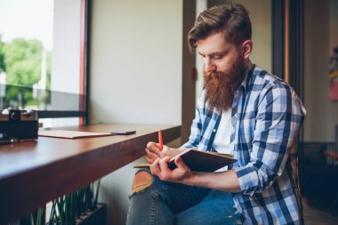 Yetenekli genç boş vaktinizi kafede not defterindeki kroki çizim rahat tişörtlü adam sakallı. Yetenekli öğrenci ödev coworking içinde oturan not defteri olarak aşağı yazma. Kopyalama alanı alanı
