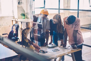 Genç profesyonel tasarımcılar tablo modern Studio toplantı sırasında planı hakkında fikirleri tartışmak mürettebatı. Erkek ve dişi Mimarlar teknoloji beyin fırtınası grafik kullanarak ofiste kroki