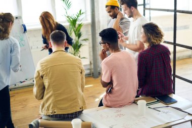 Arkadan görünüşü fikirleri tartışmak ve ofiste oturan yeni tasarım proje üzerinde birlikte hipster çocuklar yetenekli çok kültürlü grup. Yaratıcı öğrenciler yararlı mimari atölye dinleme