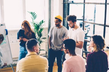 Ofiste ayakta ve eğitim beyin fırtınası sırasında fikirleri tartışmak çeşitlilik hipster çocuklar genç mürettebatı. Studio iç mimari görevinin çözüm üzerinde düşünme erkek ve kadın tasarımcılar