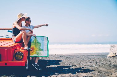 Erkek ve kadın turist yapma dur sonraki rota, çift balayı cabriolet doğum sırasında harita navigasyon seyir aşık tartışırken vintage Kiralık Araba üzerinde oturan tropik adada yolculuk sırasında
