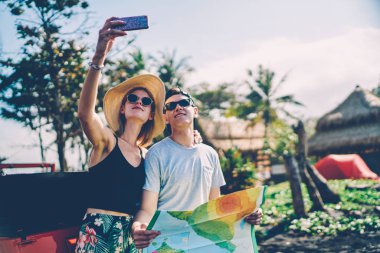 Yaz tatillerini birlikte yolculuk, cep Kiralama car yakınındaki fotoğrafı için poz aşık çift sırasında harcama zevk sevgilisi ile selfie yapmak için akıllı telefon kullanan hippi kız gülümseyerek