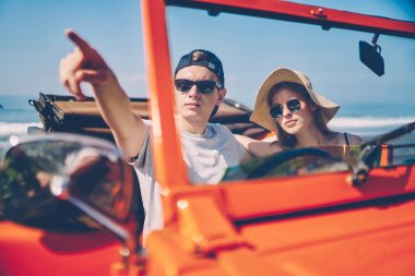 Hipster adam kız arkadaşı ile birlikte, seyahat sürüş için rota tartışırken bir şey üzerinde iki cabriolet doğum tropik adada Kiralık Araba taşıma içinde oturan aşk içinde işaret eden güneş gözlüğü