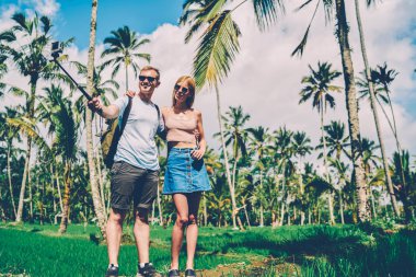 Yakışıklı olan yolculuk tropikal bir ortamda, selfie için mobil zevk hafta sonları birlikte poz hipster kaç kız arkadaşı ile resim yapmak için kamera monopod ve smartphone kullanarak