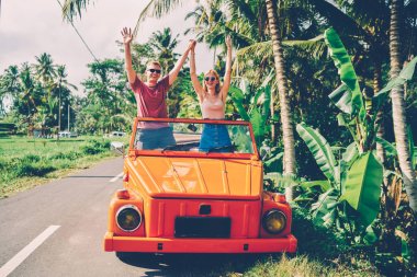 Birlikte yaz tatili ayakta Kiralama Cabriolet sırasında çok memnun duygu el yükselterek aşk heyecan çift, mutlu kız otomobil için kullanarak yolculuk sırasında serbest zaman zevk keşfetmek tropik