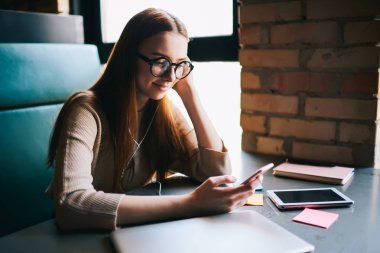 Pozitif kadında genç moda gözlük smartphone üzerinden web sitelerinde favori besteleri sörf yaparken müzik dinlemek zevk için 4 g bağlı. İyi bir ruh hali ve gadget ile dinlenme iyi görünümlü kız